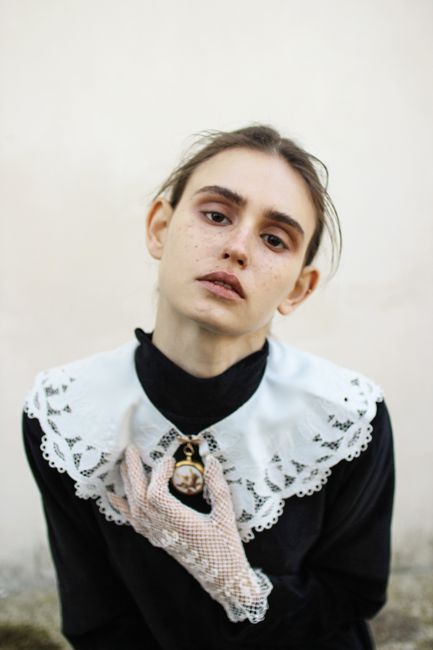 A vintage-inspired portrait of a woman in a black dress with a lace collar and gloves, exuding an emotional expression.