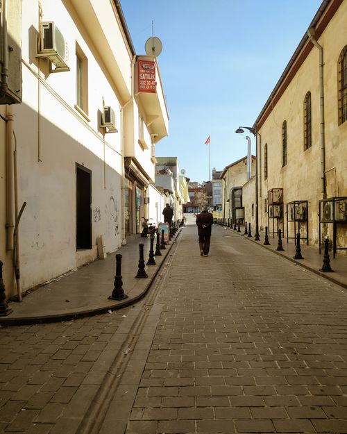 Free Peaceful narrow street with historic buildings under blue sky, ideal for travel and cityscape themes. Stock Photo