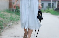 一名女子穿着休闲夏装、背着黑色手袋在户外行走