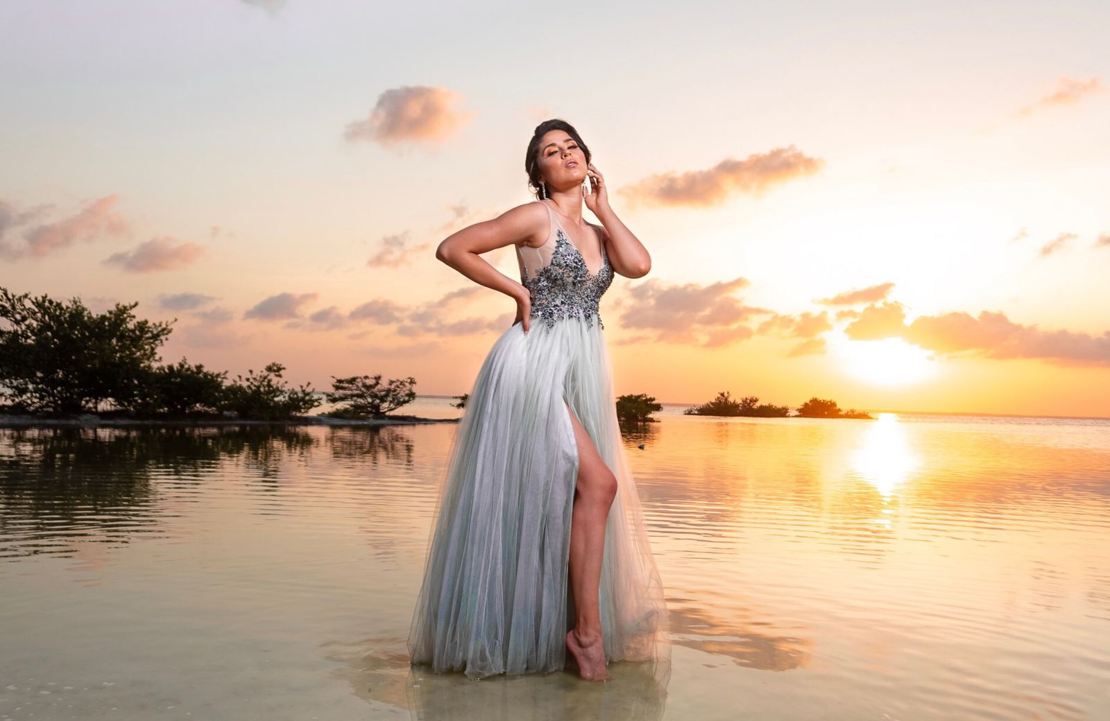 Elegant woman wearing a sophisticated vacation dress beside the ocean at sunset