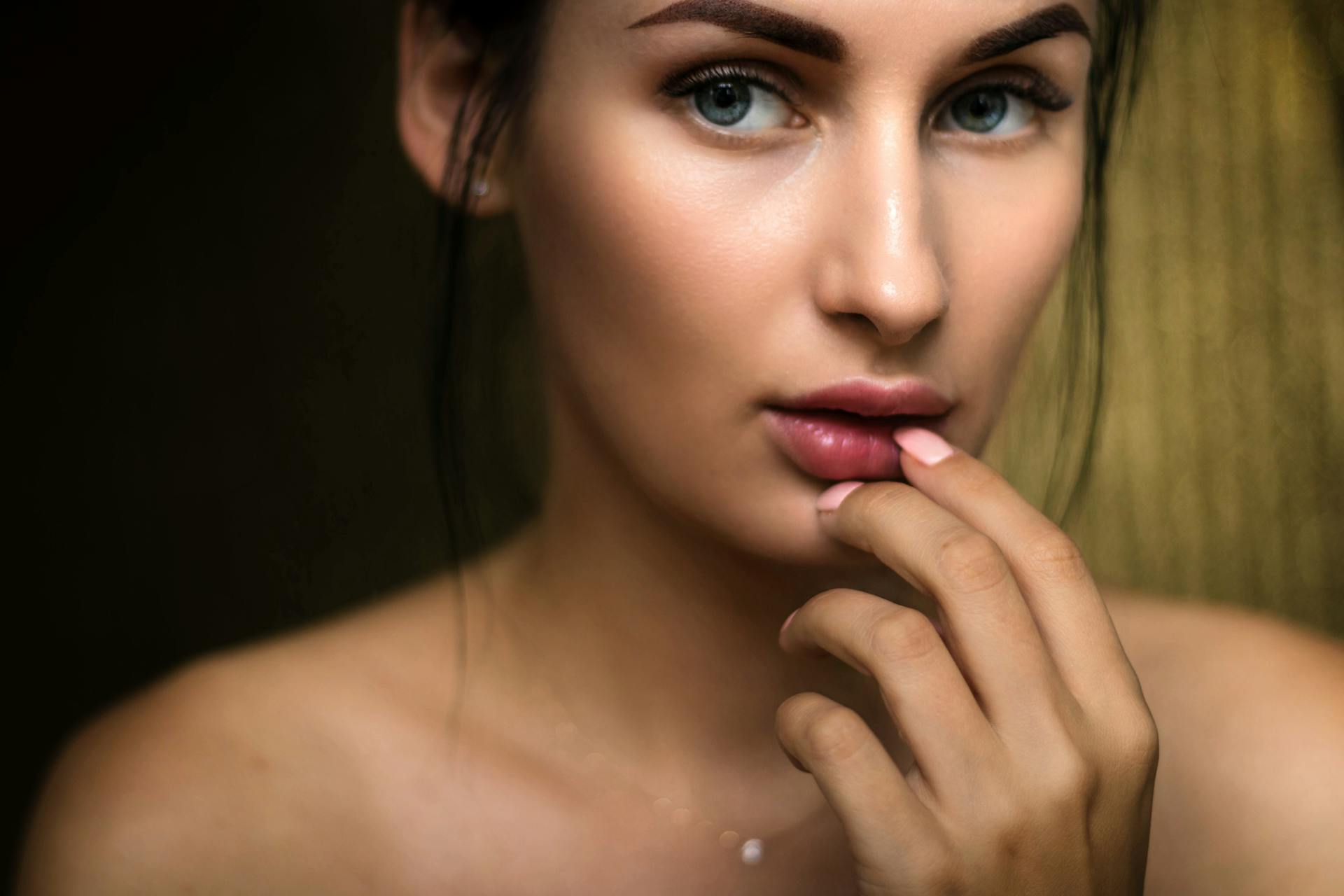 Close-up portrait capturing a woman's natural beauty with soft lighting and a thoughtful expression.