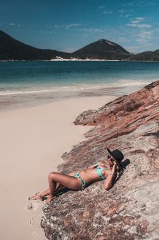 A woman sunbathing on a beautiful beach with clear blue skies and turquoise waters.