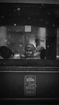 A young child looks through a rainy tram window in Istanbul, Turkey.