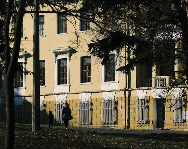 Parent And Child Walking Along A Building