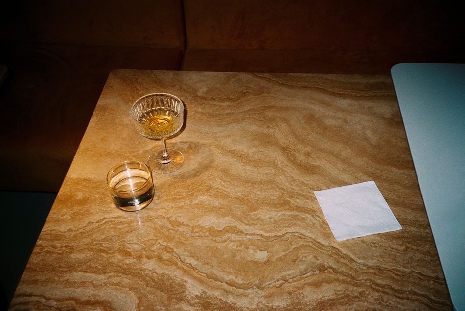 Stylish tabletop scene featuring drinks on marble surface with a napkin, evoking a retro vibe.