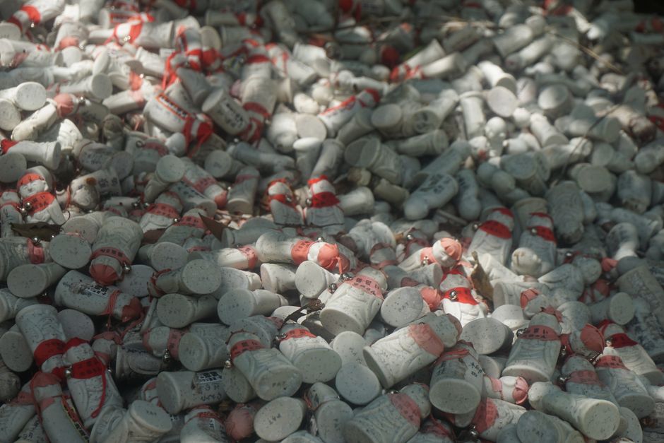 A multitude of painted figurines with red decorations densely covering the ground outdoors.