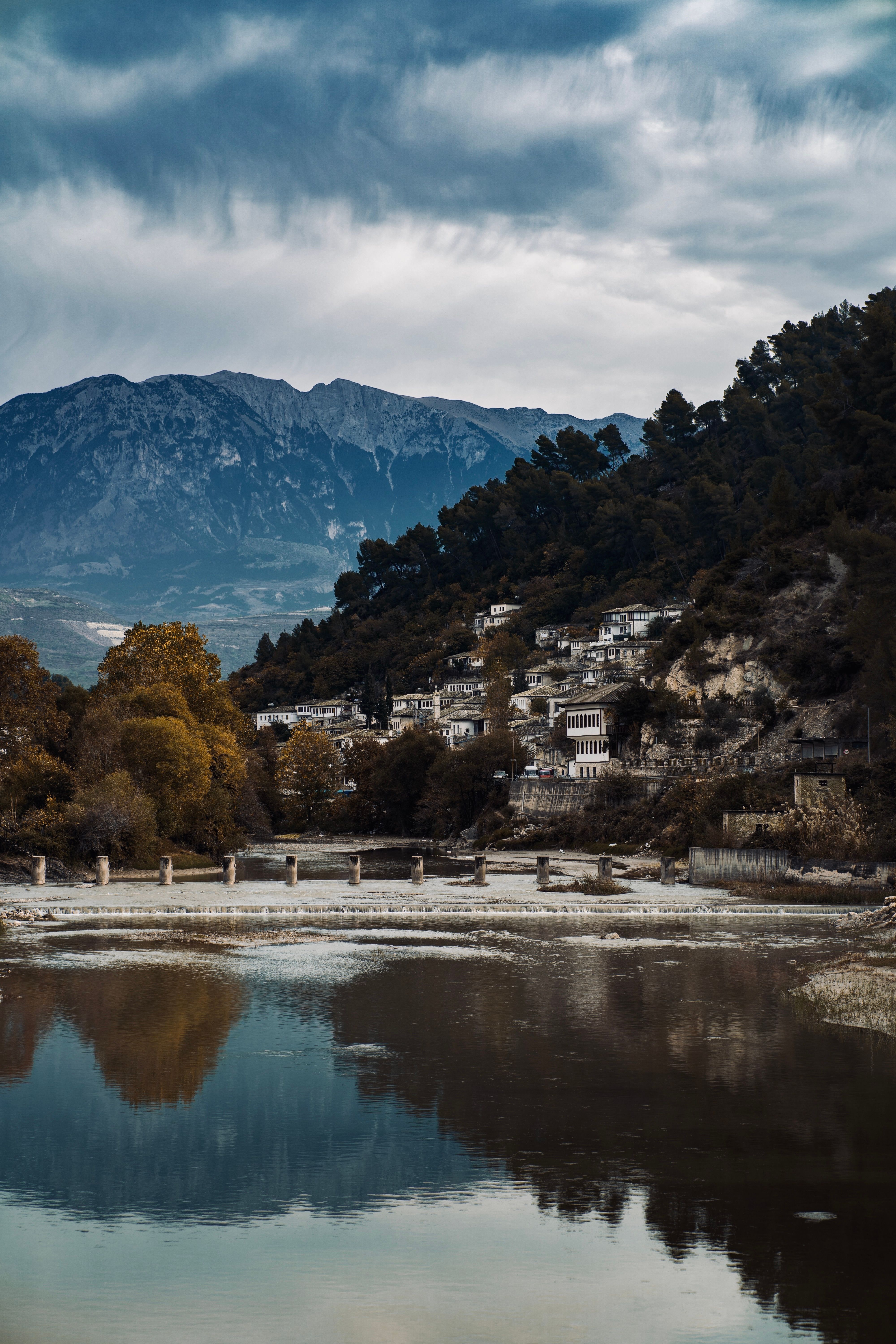 Picturesque landscape of Berat, Albania, with mountains and a serene river reflection.