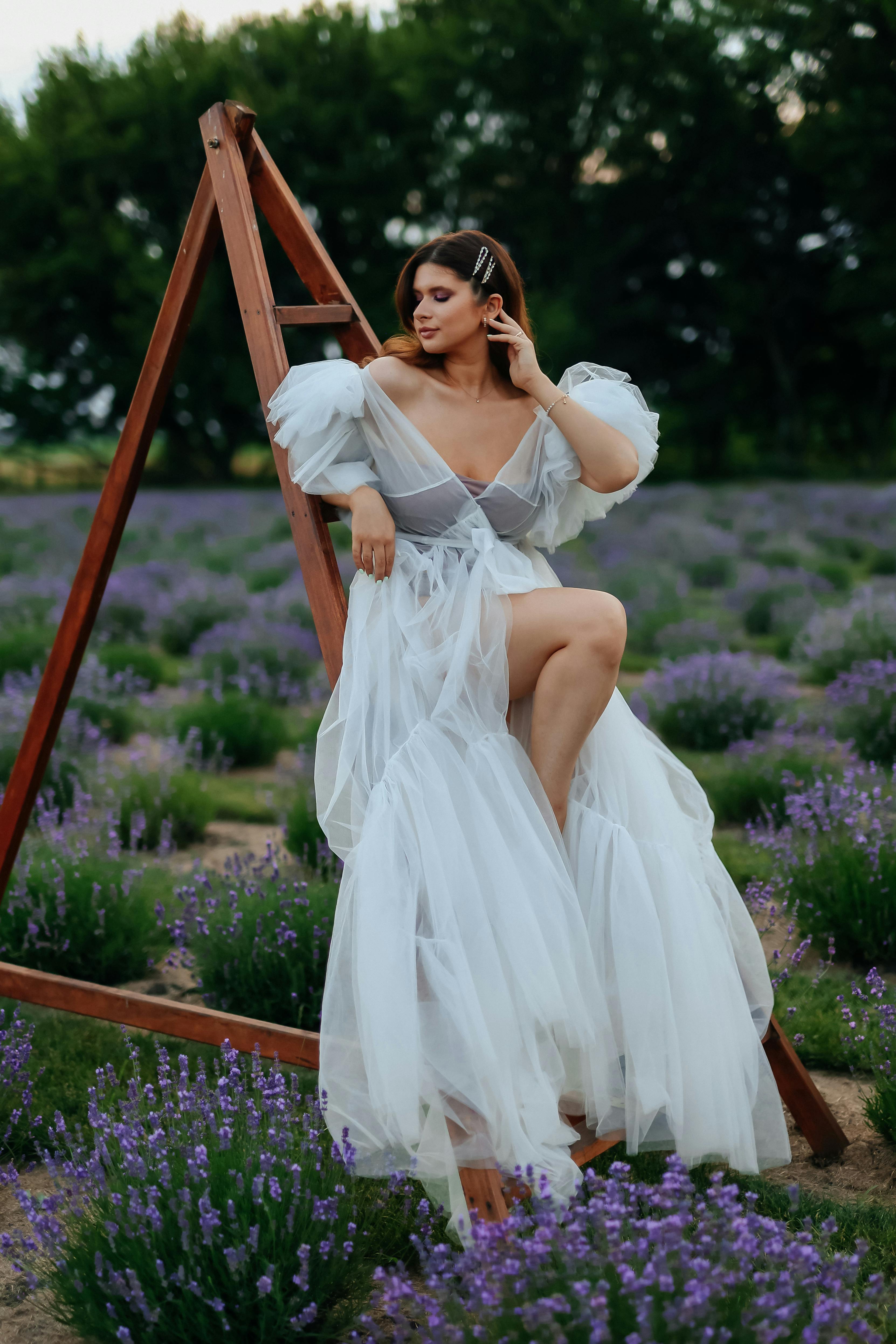 A woman in a white dress posing in a lavender field, exuding grace and elegance.