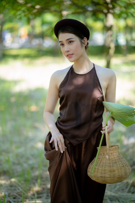 Beautiful woman in brown attire holding a basket in a serene outdoor setting.