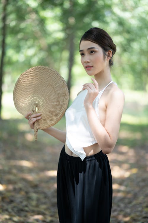 Shallow Focus of a Beautiful Woman Holding a Woven Hand Fan