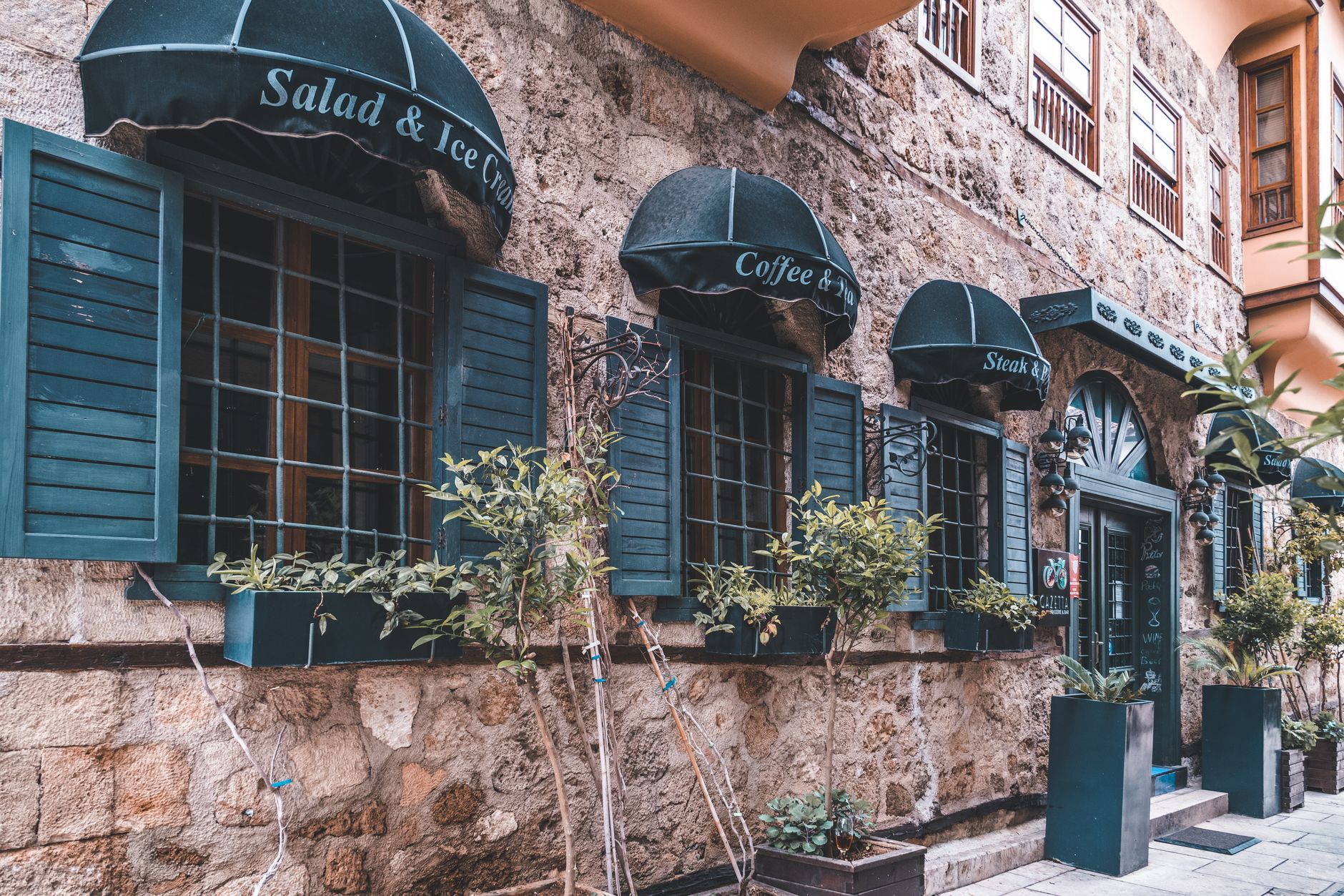 Quaint stone restaurant facade with green awnings and shutters. Ideal for cozy dining imagery.