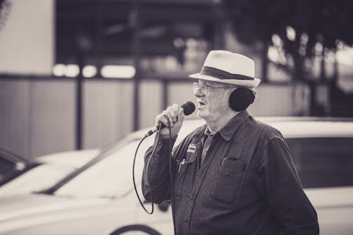 Grayscale Photo of Elderly Man Holding Microphone
