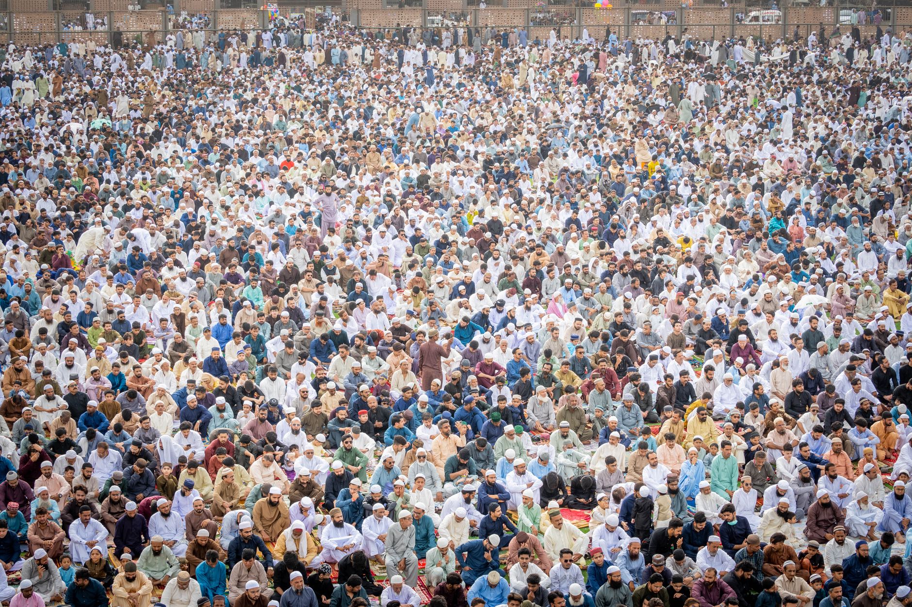 A vast assembly of Muslims in traditional clothing participating in a religious event outdoors.