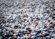 An aerial view of a large group of people bowing in prayer, showcasing unity in religious practice.