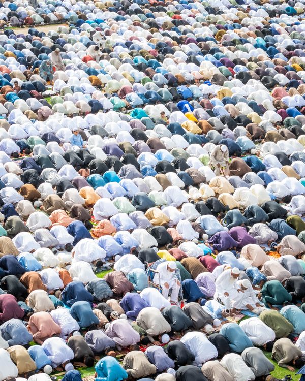 Aerial view of a vast congregation of Muslims kneeling and bowing in prayer at Masjid al-Haram