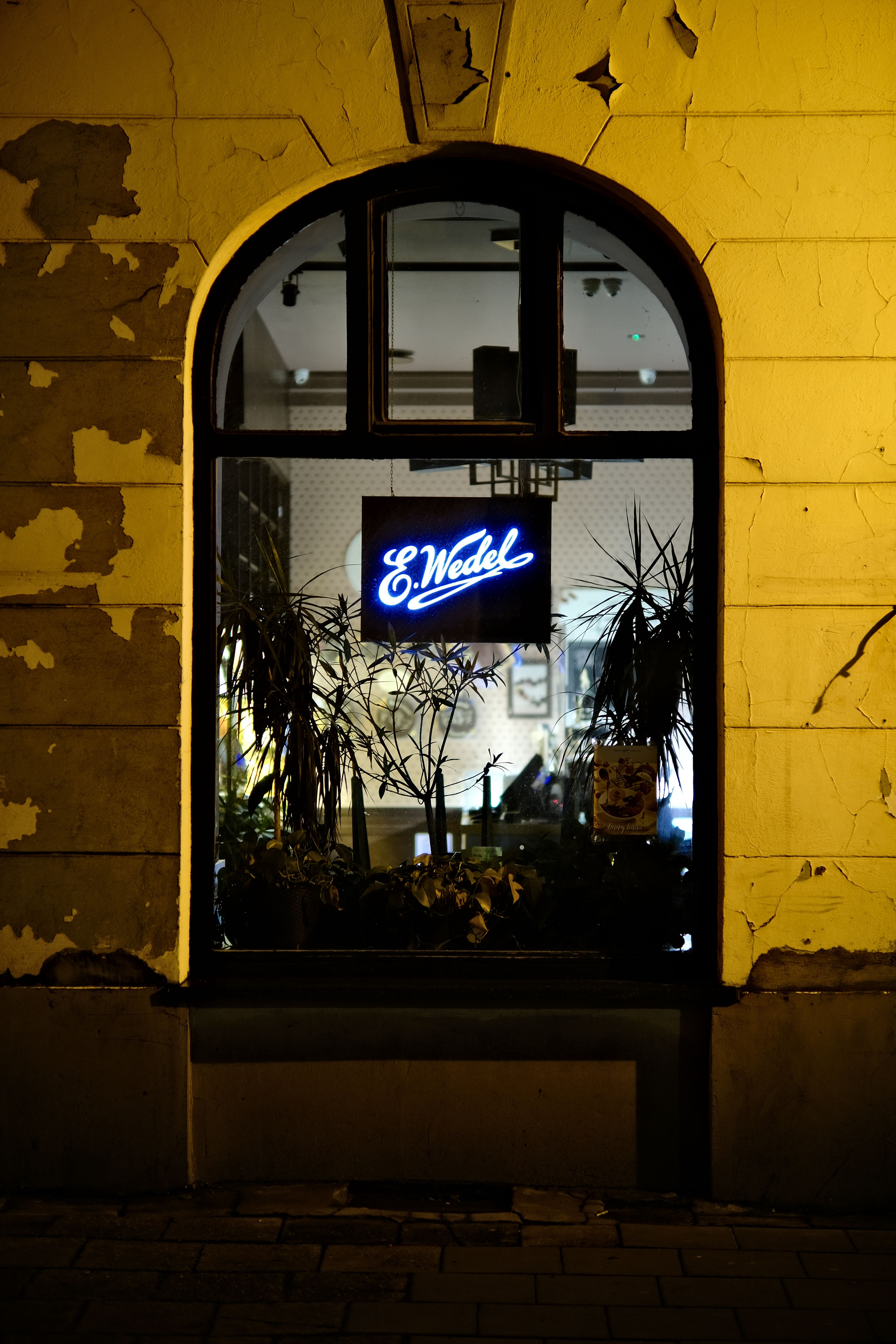 Captivating view of a neon-lit window on a rustic yellow wall at night.