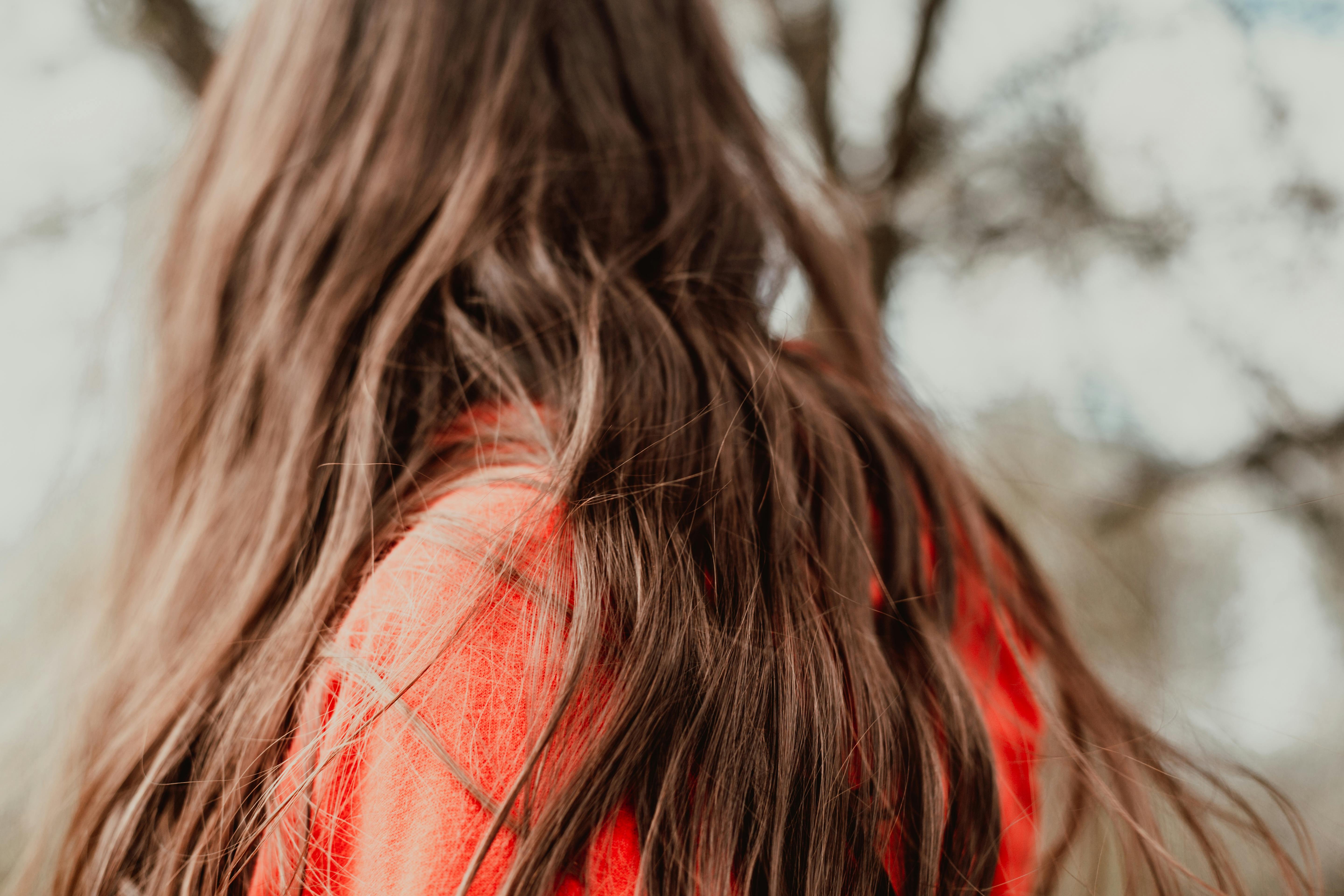 A close-up of a woman with long, flowing brown hair. Blurred background adds depth.