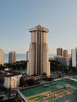 A tall skyscraper in Benidorm, Spain, with the ocean in the background at sunset.