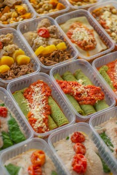An assortment of healthy, colorful meal prep boxes featuring vegetables, grains, and proteins.