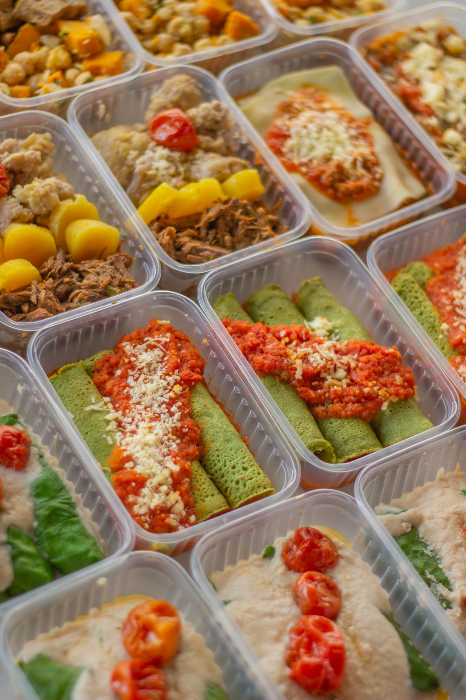 Assortment of colorful prepared meal containers with vegetables, grains, and protein, representing a chef-made meal delivery variety