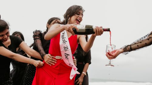 Free Joyful bride-to-be celebrating with friends, pouring red wine outdoors in vibrant atmosphere. Stock Photo