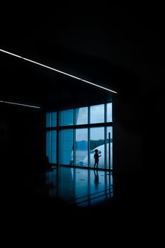 Silhouette of a boy looking through windows at an airport terminal in Cancún, Mexico.