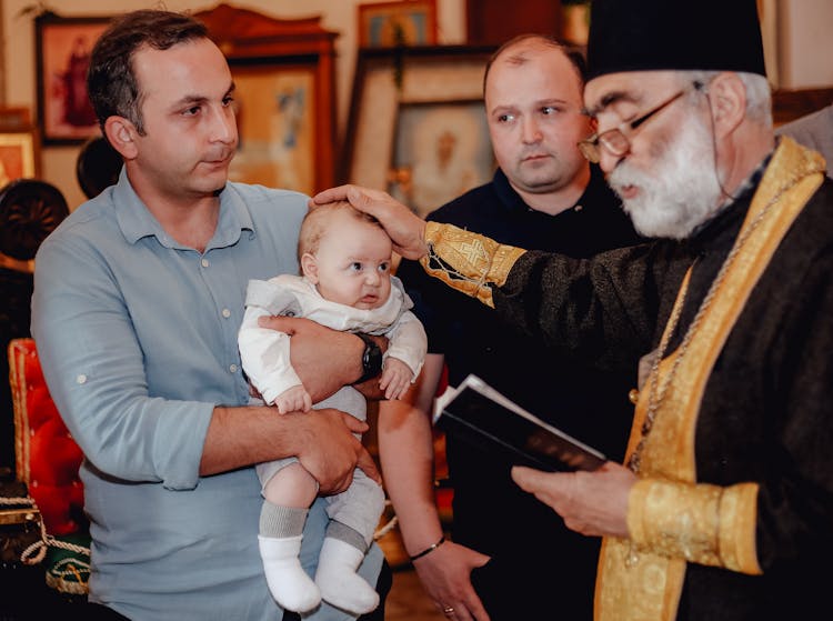 Man Holding A Baby During A Religious Sacrament