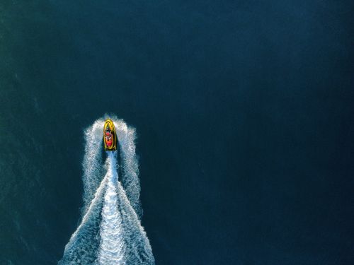 Free Drone shot of a speedboat on the sea leaving a white trail, capturing movement from above. Stock Photo