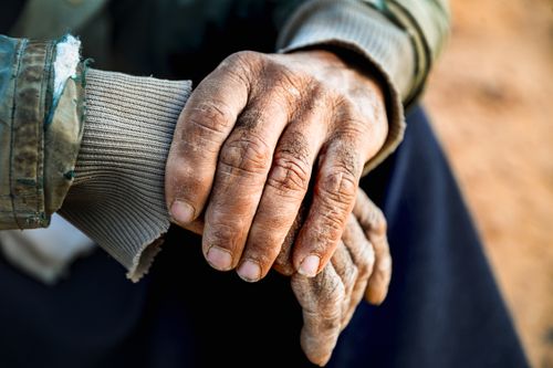 Free A touching close-up of elderly hands embracing outdoors, symbolizing care and warmth. Stock Photo