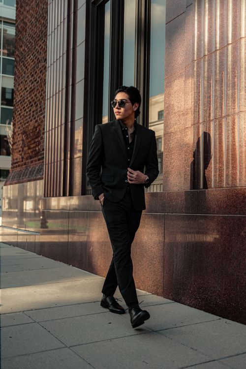Free Young man in a sleek suit walking in the city with sunglasses. Stock Photo