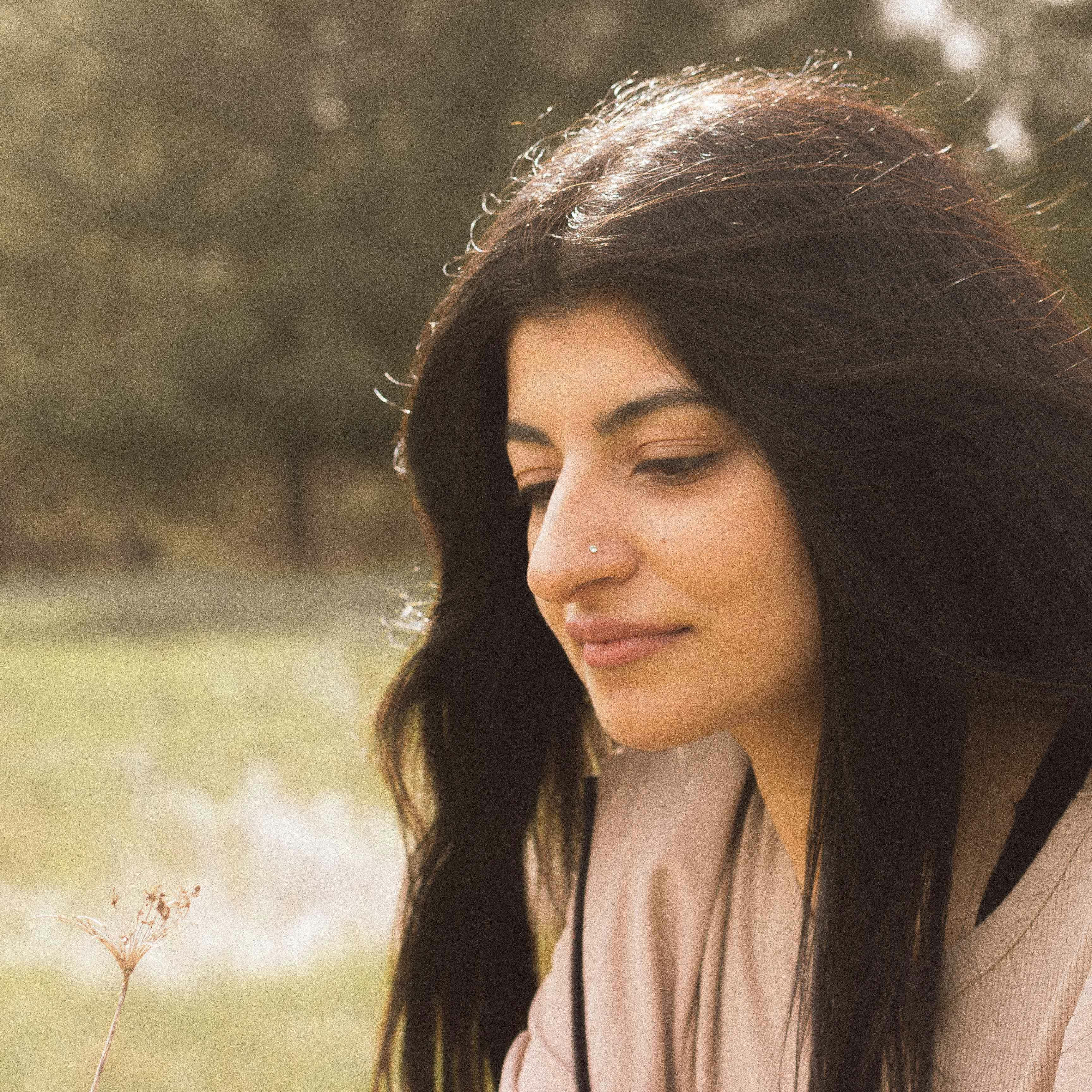 A serene portrait of a woman enjoying a quiet moment in a sunlit meadow.