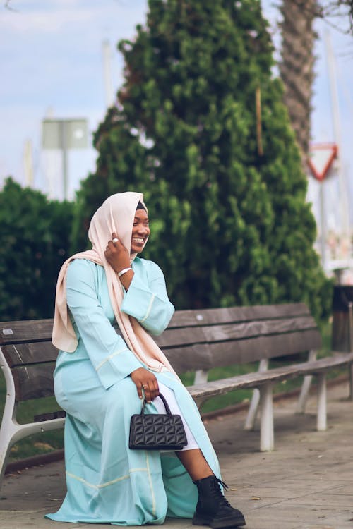 A Woman in Beige Hijab Sitting on Wooden Bench