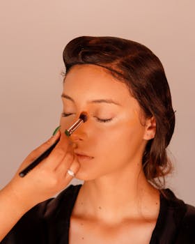 Close-up of a woman receiving professional makeup in a studio. Ideal for beauty industry themes.