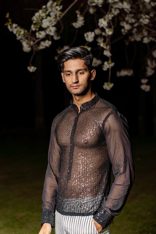 Free Stylish man in sophisticated see-through outfit under blooming blossoms. Stock Photo