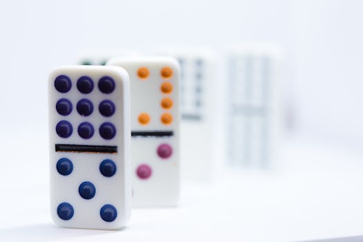 Close-up of colorful dominoes lined up on a white surface, showcasing vibrant dots.