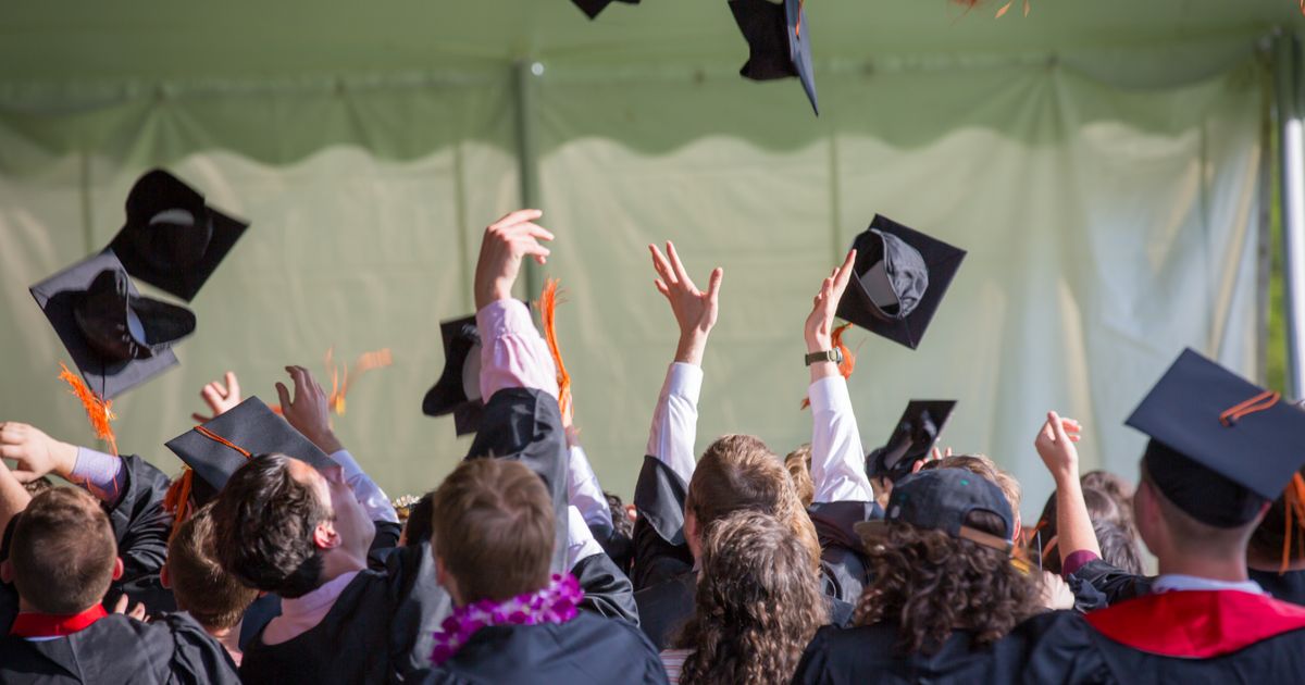 Graduates celebrating and throwing caps at a ceremony
