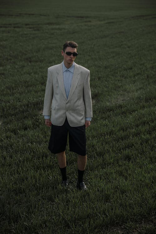 Free Man in White Suit Jacket and Black Shorts Standing on Green Grass Field Stock Photo