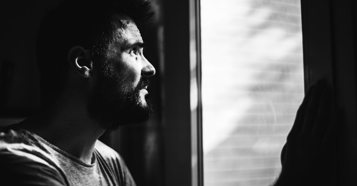 Person standing at a window, looking out, deep in thought