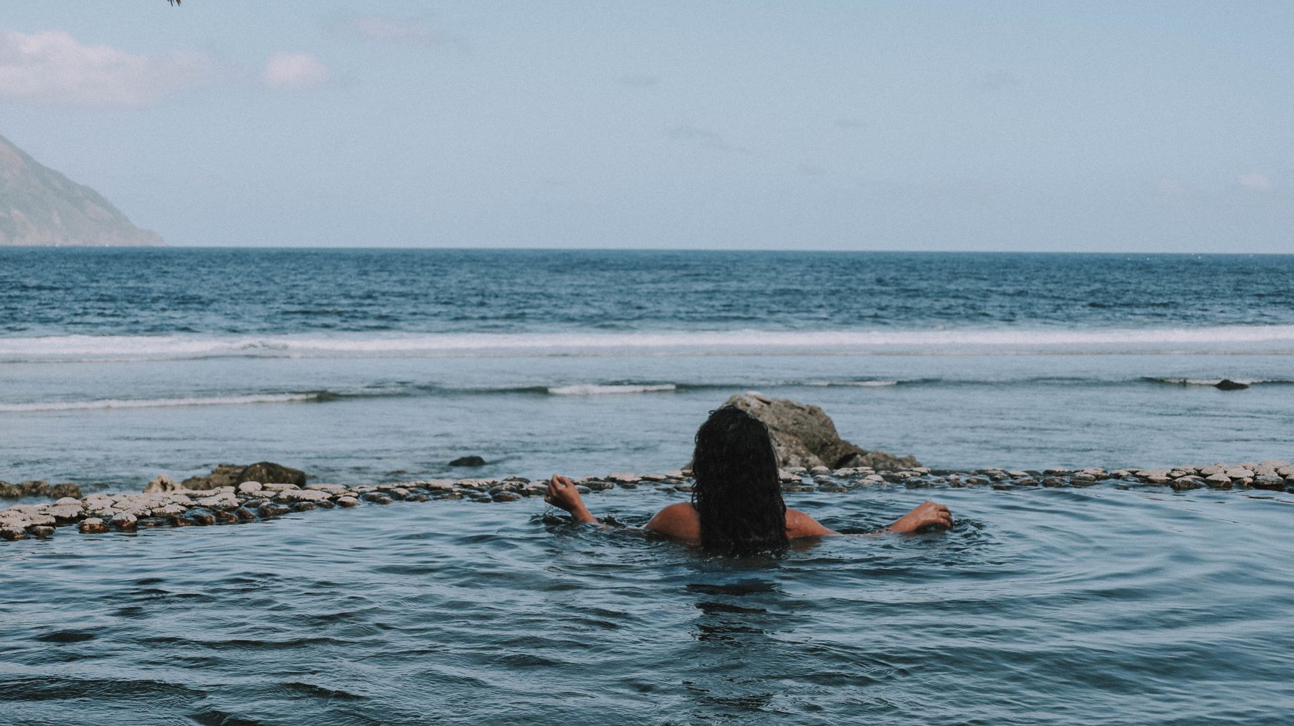 Person enjoying a serene view in an infinity pool overlooking the ocean in Cagayan Valley, Philippines.
