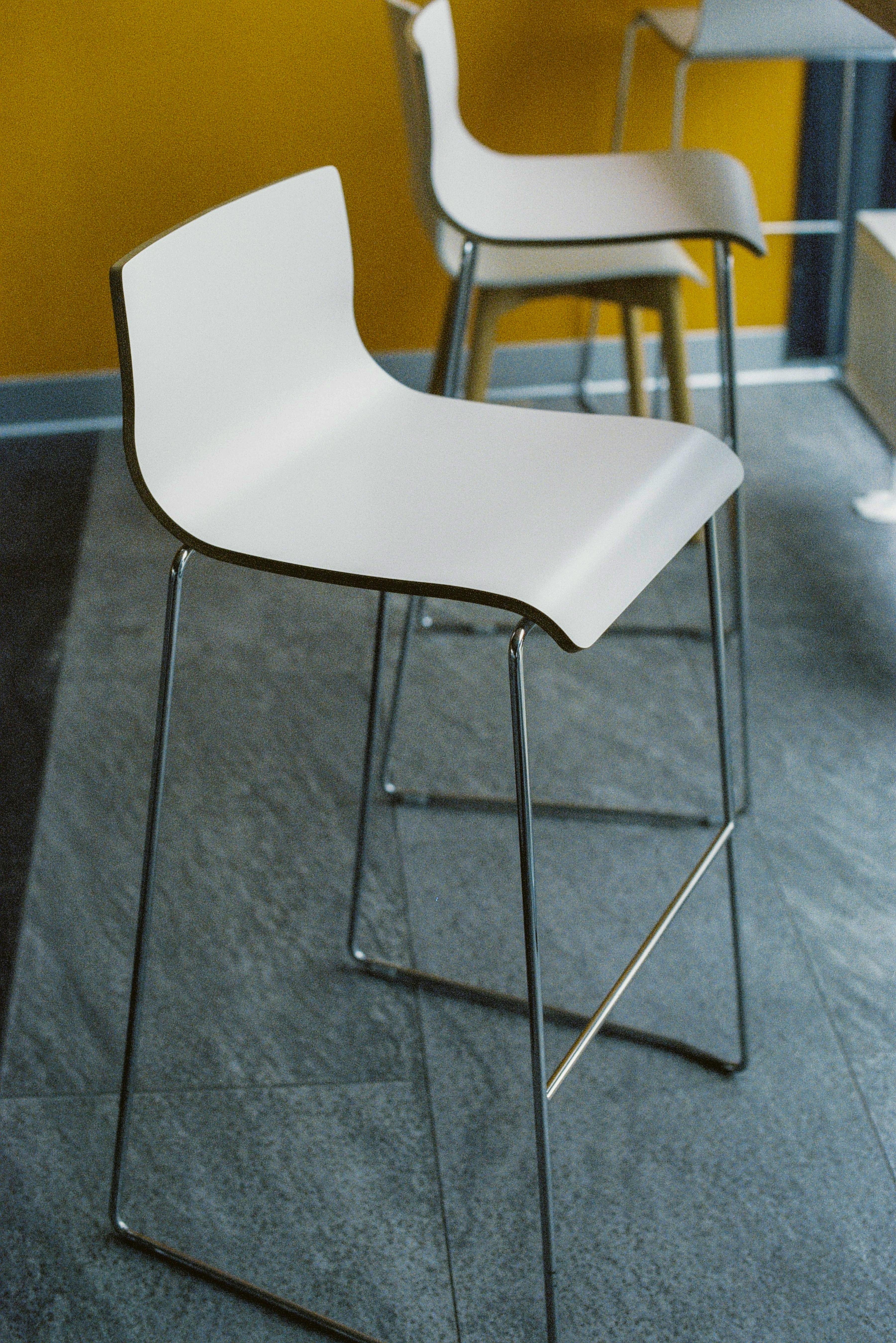 Contemporary white bar stools in a stylish interior setting with a vibrant yellow wall.