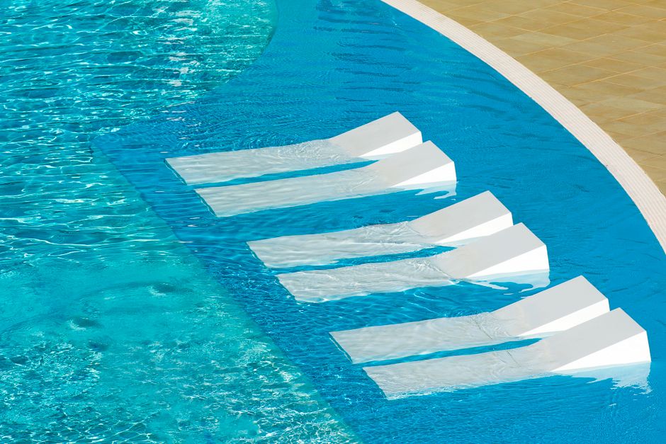 residents relaxing on half-submerged water loungers - apartments with pool residents relaxing on half-submerged water loungers - apartments with pool