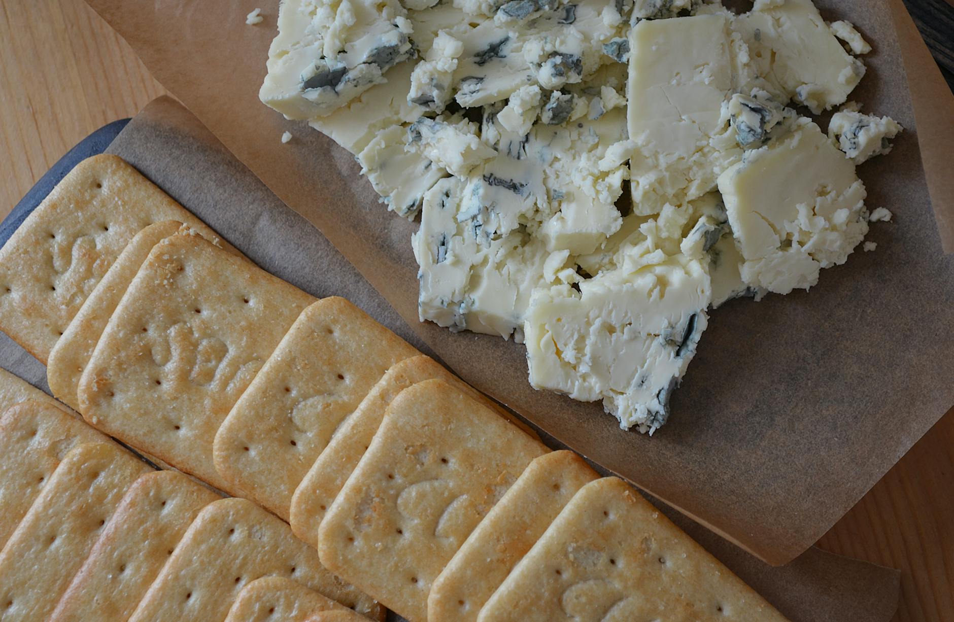 Cheese And Crackers On A Wooden Board With A Variety Of Cheeses And Whole Grain Crackers
