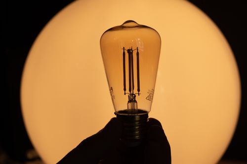 Free lightbulb in the dark with gold lights in the background, great ideas coming, creativity is rising Stock Photo