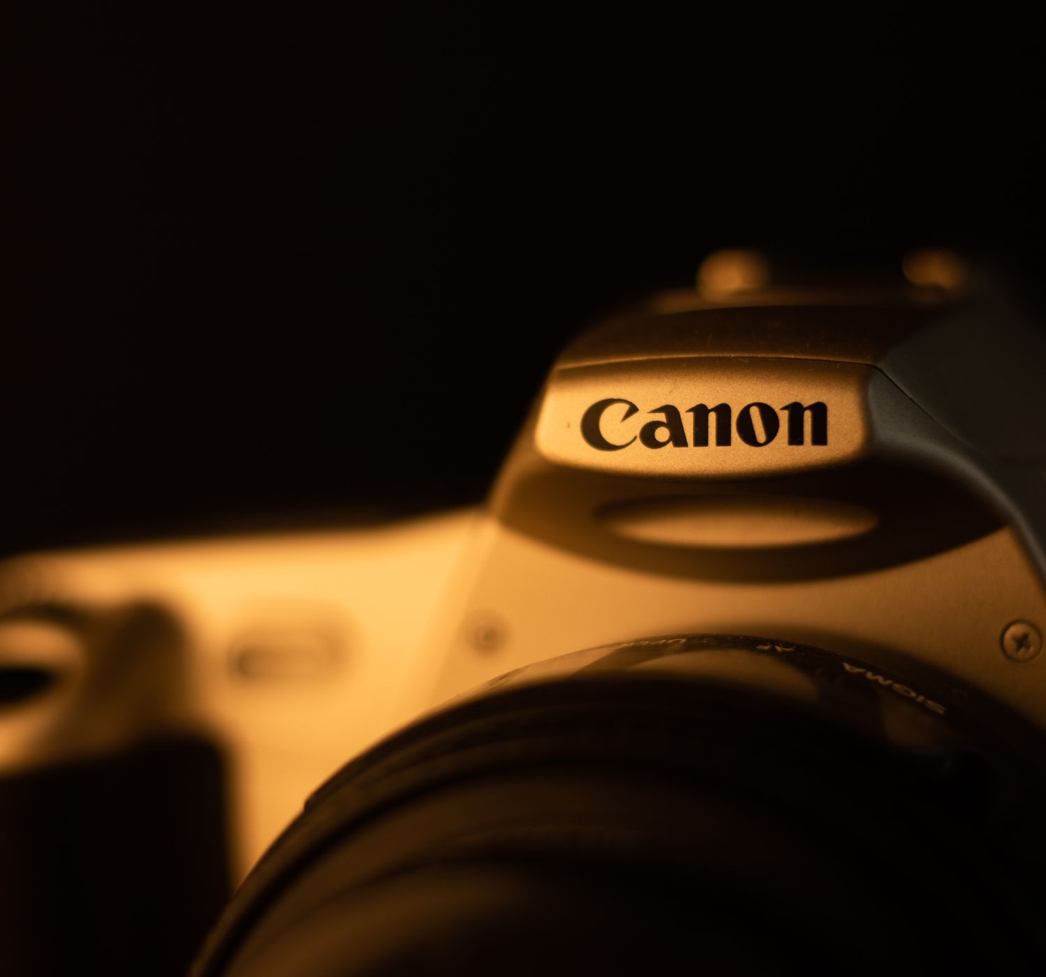 Artistic closeup of a vintage Canon camera in low light, showcasing detail and shadow.