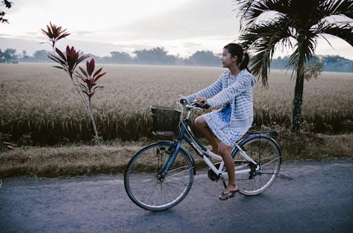 Woman Riding on Blue and White Bicycle