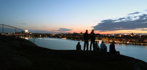 People Standing on Cliff Near River during Golden Hour