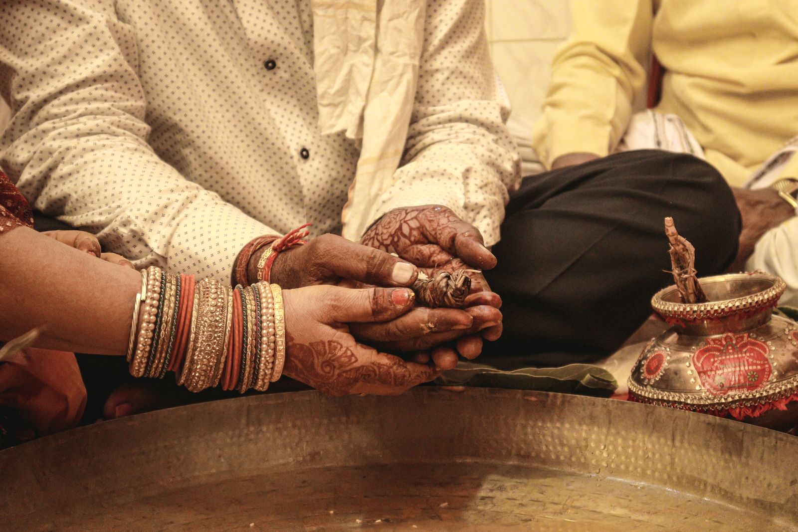 Close up of hands over a brass vessel during the kanyadaan.