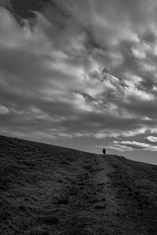 Grayscale Photography of a Person Standing on a Hill