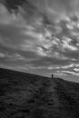 Silhouette of Person Standing on Hill Under Cloudy Sky