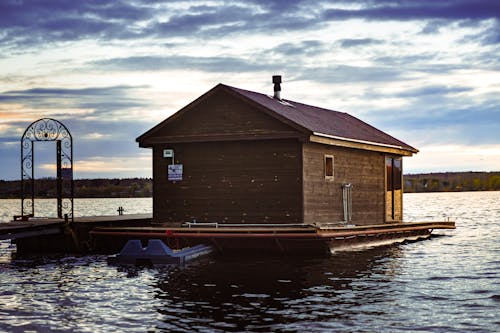 Brown Wooden House on a River Under Cloudy Sky